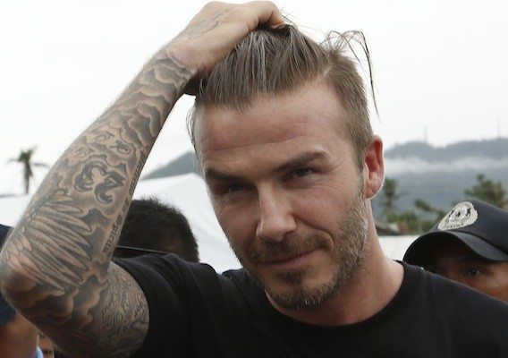 Former England soccer captain David Beckham touches his hair as he walks back to his vehicle after visiting an evacuation centre nearly 100 days after super Typhoon Haiyan devastated Tacloban city in central Philippines February 13, 2014. Local officials said Beckham is one of the biggest donors to areas devastated by super typhoon Haiyan in central Philippines. REUTERS/Erik De Castro (PHILIPPINES - Tags: SPORT DISASTER HEADSHOT) - RTX18Q21
