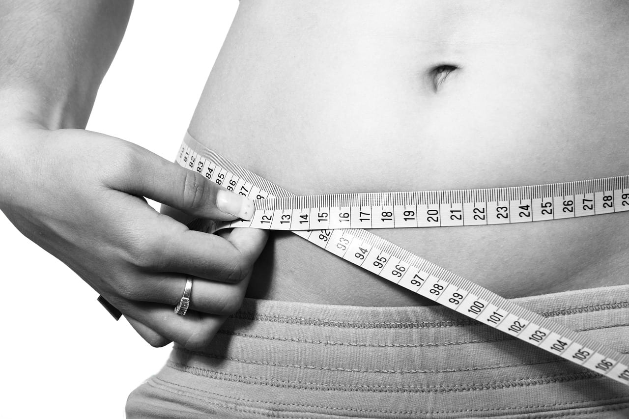 Woman measuring her waistline after using natural weight loss pills